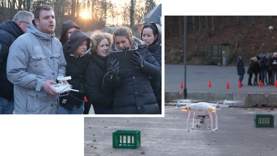 En gruppe mennesker står udenfor som en del af en firma aktivitet, og en af dem holder en fjernbetjening, mens en anden ser på en skærm. Man kan se en drone, der flyver rundt.