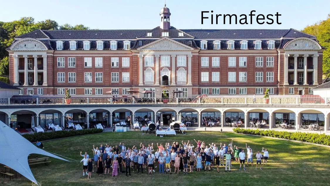 Billedet viser en stor gruppe mennesker, der står samlet foran Hotel Koldingfjord. Bygningen er en imponerende, klassisk struktur med mange vinduer og en bred balkon på første sal. Foran hotellet er der en stor, velplejet græsplæne, hvor folkene står, mange med armene løftet i glæde og jubel. Dette billede symboliserer en firmafest eller et stort arrangement, der afholdes på Hotel Koldingfjord, hvilket fremgår af den klare tekst "Firmafest" øverst til højre på billedet. Hotellet og dets elegante omgivelser skaber en formel, men festlig atmosfære, der er ideel til store virksomhedsarrangementer og sammenkomster.