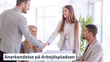 Billedet viser en gruppe forretningsfolk på en arbejdsplads, hvor en mand og en kvinde giver hinanden et håndtryk og smiler. Andre kolleger ser glade og tilfredse ud, mens de observerer interaktionen. Teksten "Anerkendelse på Arbejdspladsen" er tydeligt synlig nederst i billedet. Dette billede illustrerer betydningen af anerkendelse og positiv interaktion på arbejdspladsen, hvilket bidrager til et motiverende og støttende arbejdsmiljø.