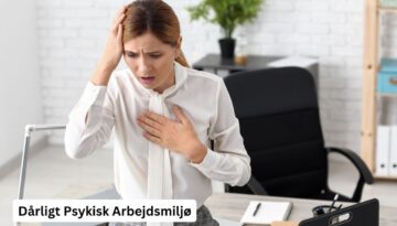 Billedet viser en kvinde på en arbejdsplads, der ser stresset og urolig ud. Hun holder en hånd mod panden og den anden mod brystet, hvilket kan indikere angst eller stress. Teksten "Dårligt Psykisk Arbejdsmiljø" er synlig i nederste venstre hjørne af billedet. Dette billede illustrerer konsekvenserne af et dårligt psykisk arbejdsmiljø og vigtigheden af at adressere mental sundhed på arbejdspladsen.