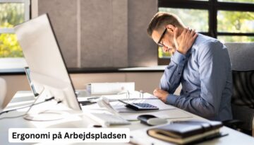 Billedet viser en mand, der sidder ved et skrivebord og ser ud til at have nakkesmerter. Han holder sin nakke med den ene hånd, mens han arbejder ved computeren. Teksten "Ergonomi på Arbejdspladsen" er synlig i nederste venstre hjørne af billedet. Dette billede illustrerer vigtigheden af god ergonomi på arbejdspladsen for at undgå arbejdsrelaterede skader og forbedre medarbejdernes velbefindende.